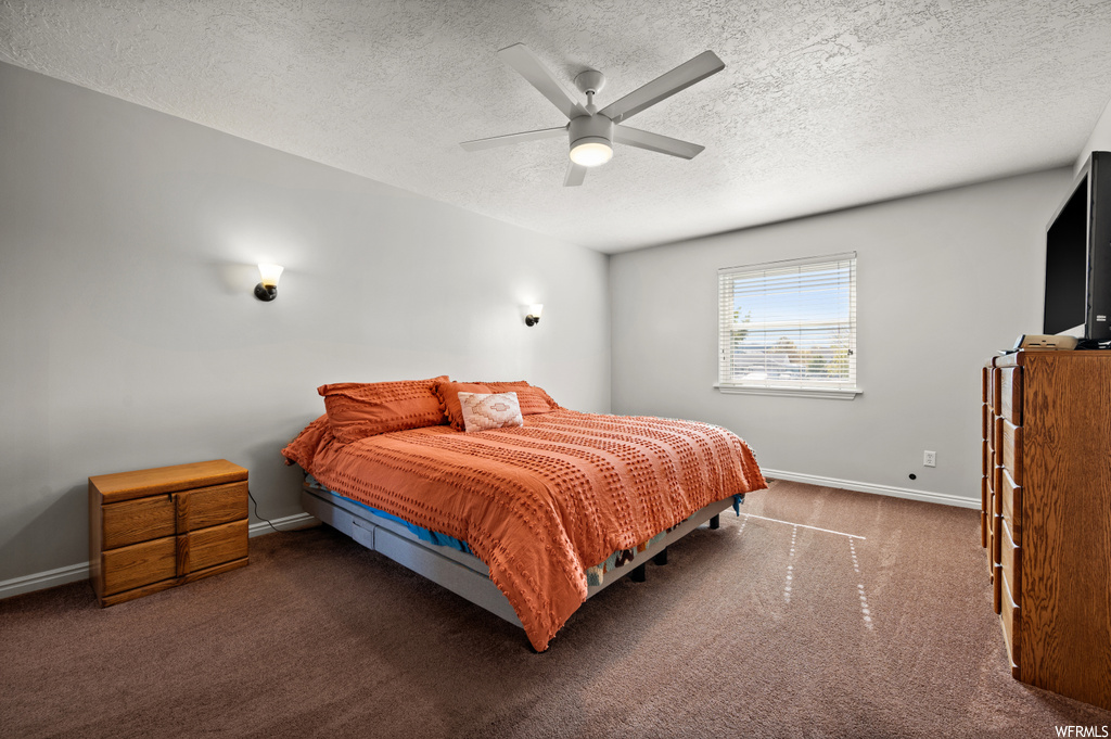 Bedroom featuring ceiling fan, a textured ceiling, and dark carpet