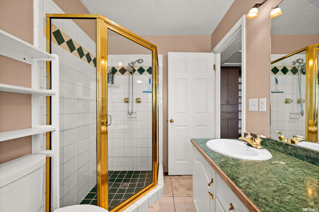 Bathroom featuring a textured ceiling, tile floors, walk in shower, and oversized vanity
