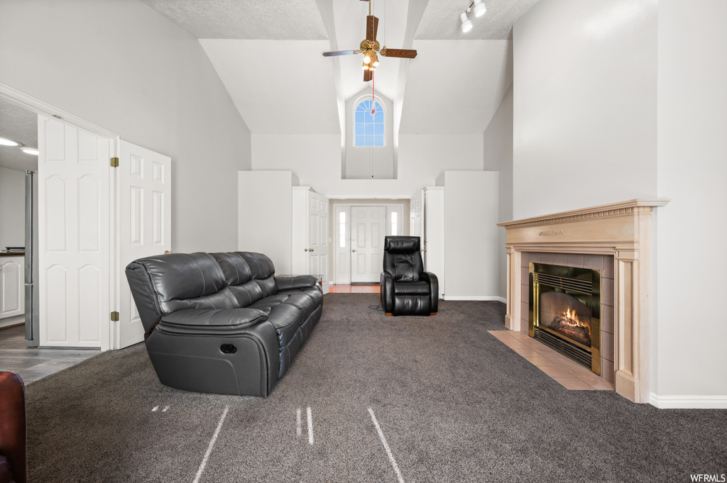 Living room featuring ceiling fan, a fireplace, high vaulted ceiling, and light colored carpet