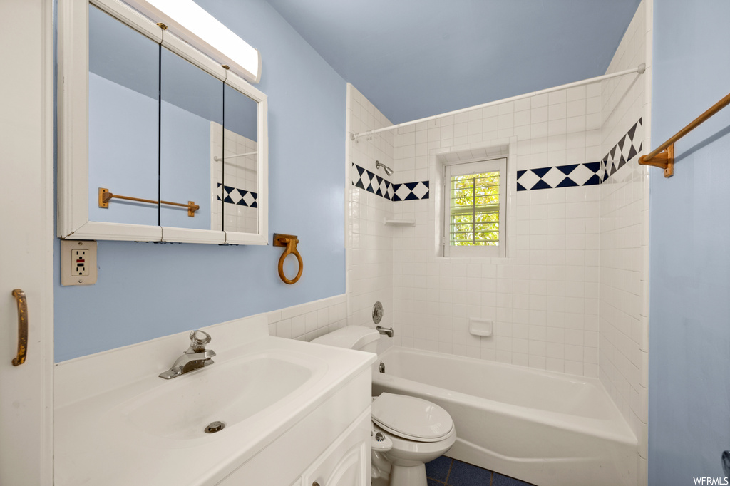 Full bathroom featuring oversized vanity, tile flooring, tiled shower / bath combo, and toilet