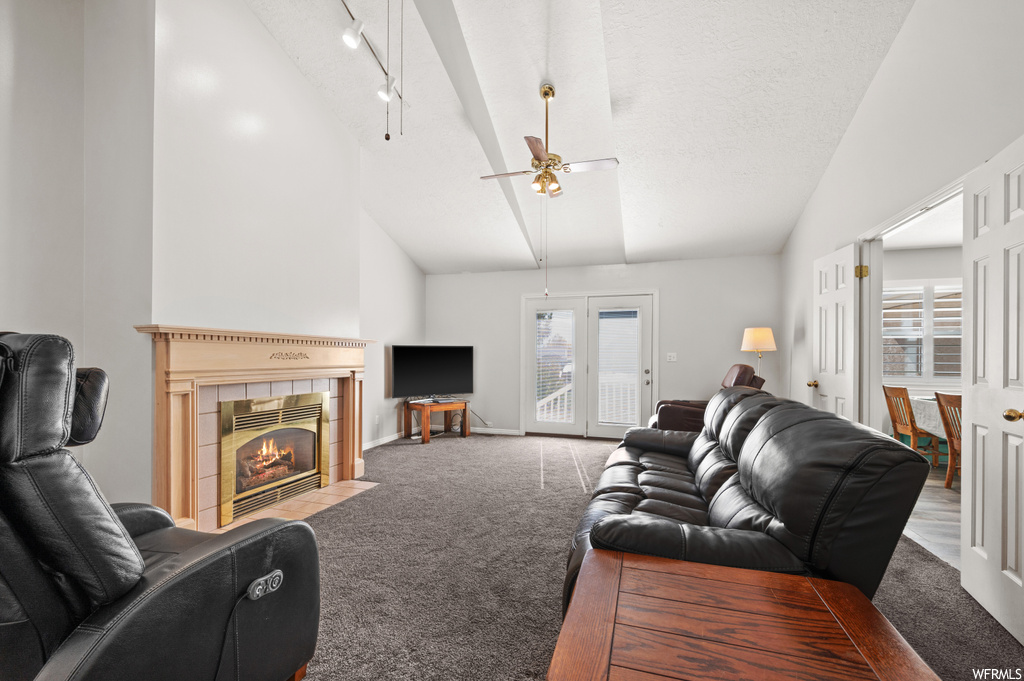 Living room featuring light carpet, high vaulted ceiling, ceiling fan, track lighting, and a fireplace