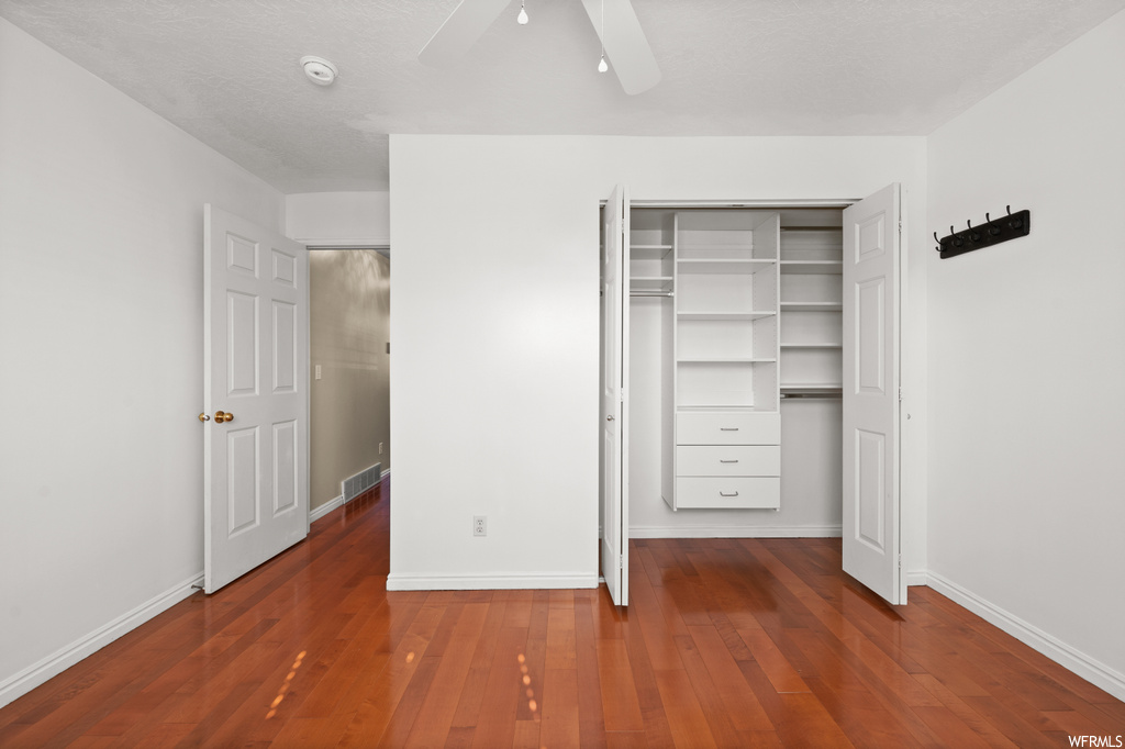 Unfurnished bedroom featuring a closet, ceiling fan, and dark hardwood / wood-style floors