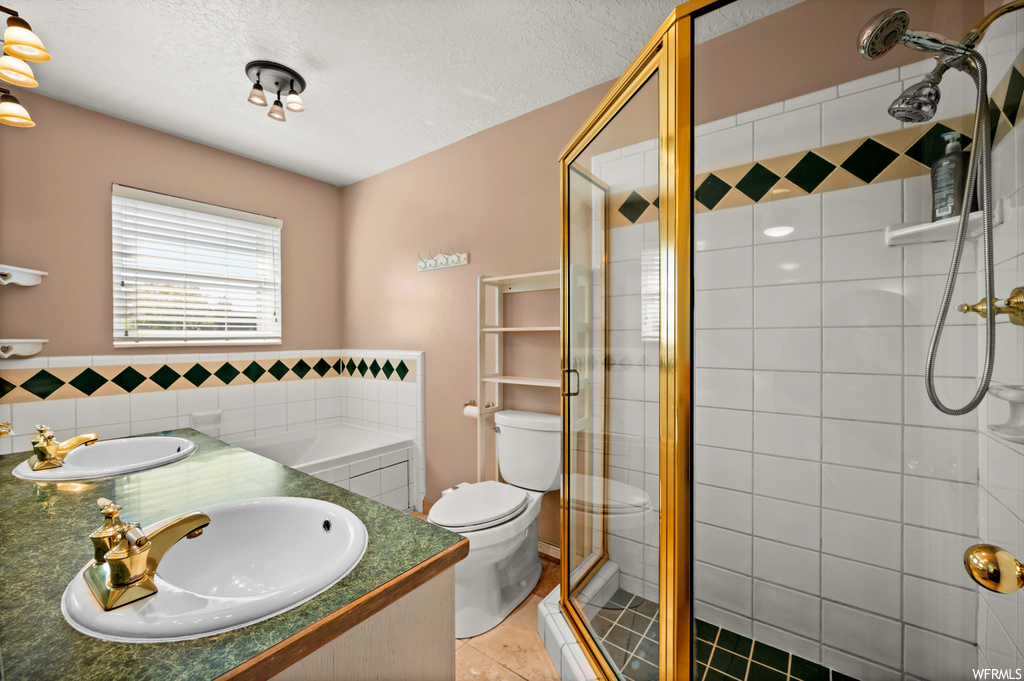 Bathroom with tile flooring, a textured ceiling, toilet, a shower with shower door, and vanity with extensive cabinet space