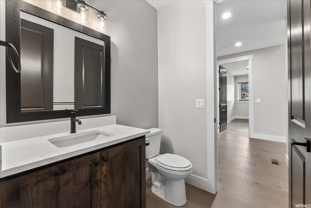 Bathroom featuring hardwood / wood-style flooring, large vanity, and toilet