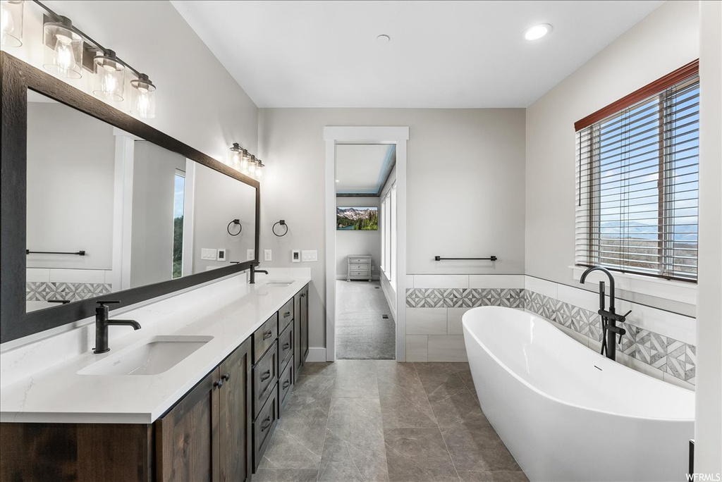 Bathroom with tile floors, a tub, and dual bowl vanity