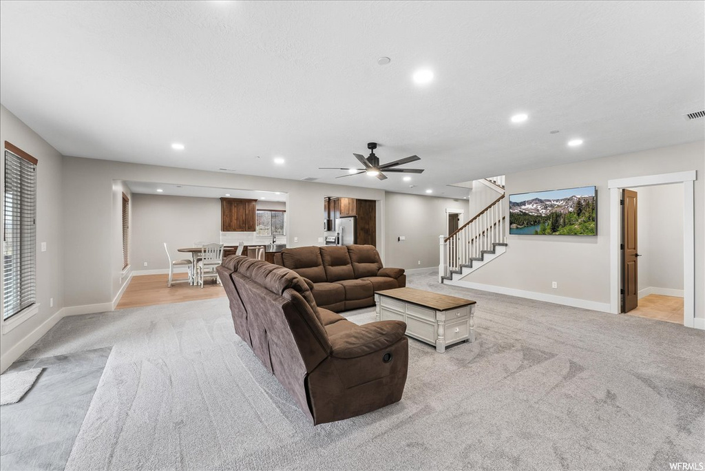 Carpeted living room with a wealth of natural light and ceiling fan