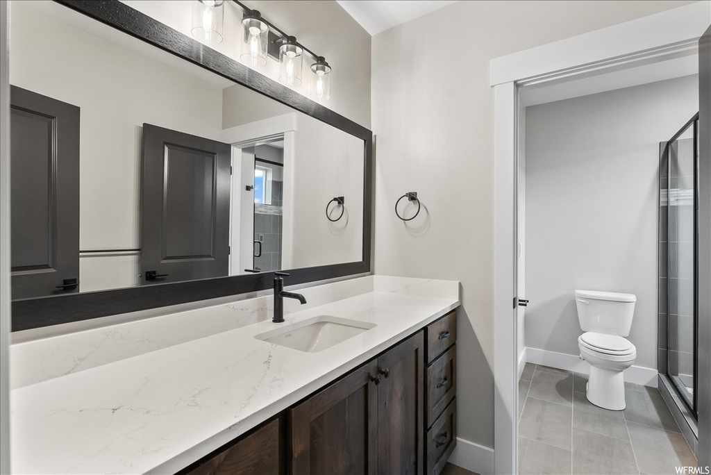 Bathroom with tile flooring, walk in shower, toilet, and vanity with extensive cabinet space