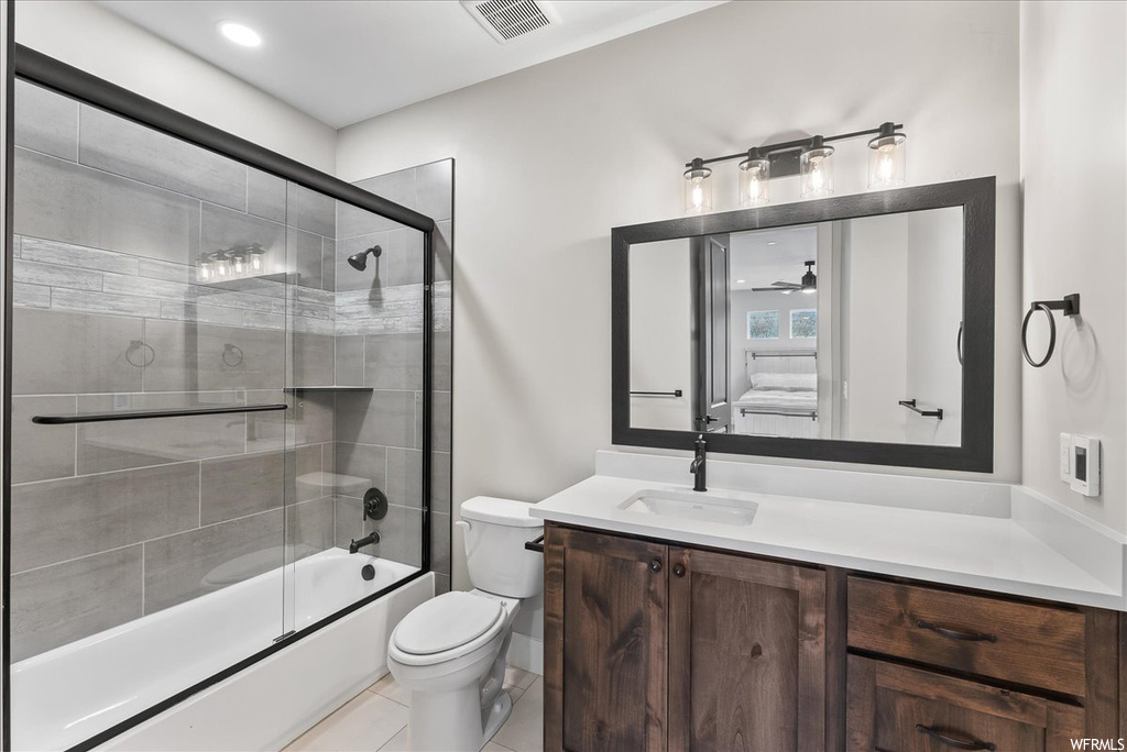 Full bathroom featuring tile flooring, toilet, vanity, combined bath / shower with glass door, and ceiling fan