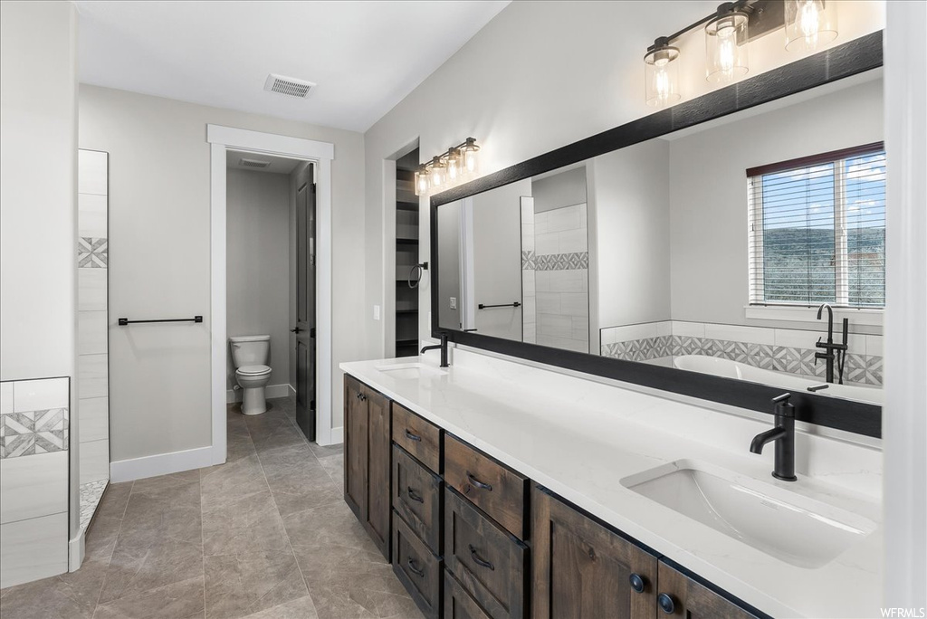 Full bathroom with toilet, separate shower and tub, dual sinks, tile floors, and vanity with extensive cabinet space