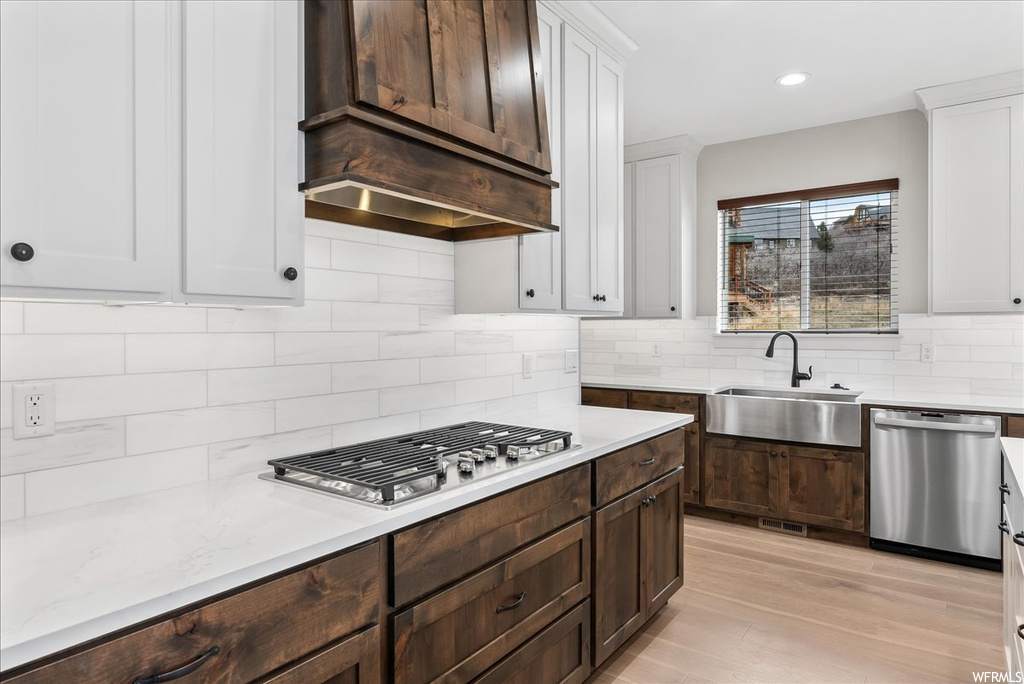 Kitchen featuring sink, tasteful backsplash, stainless steel appliances, and white cabinetry