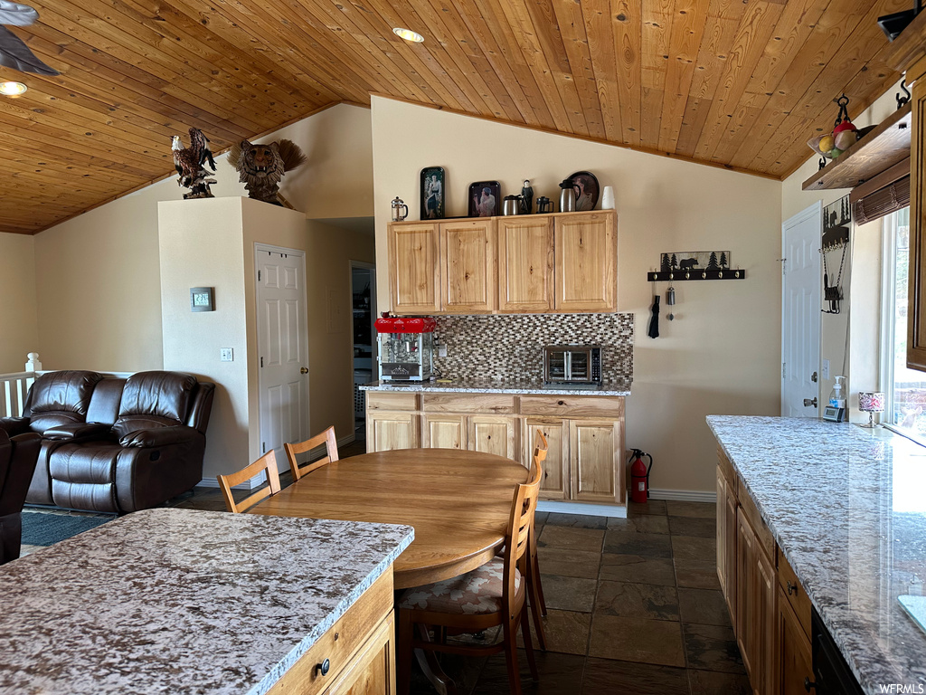 Kitchen with tasteful backsplash, dark tile floors, lofted ceiling, light brown cabinetry, and wooden ceiling