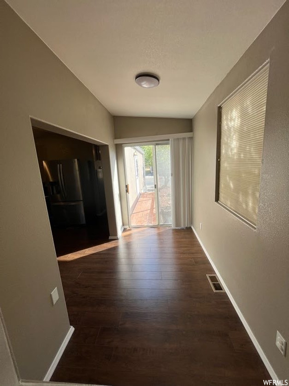 Hallway with lofted ceiling and dark wood-type flooring