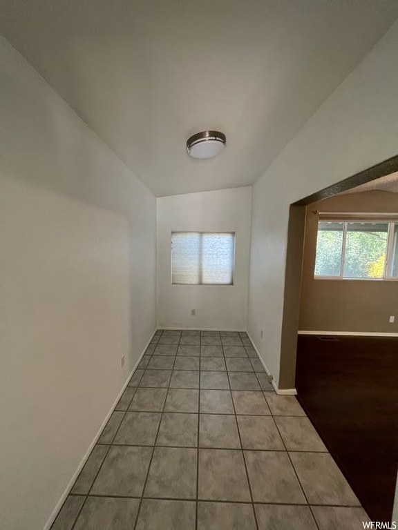 Unfurnished room featuring light tile flooring and lofted ceiling