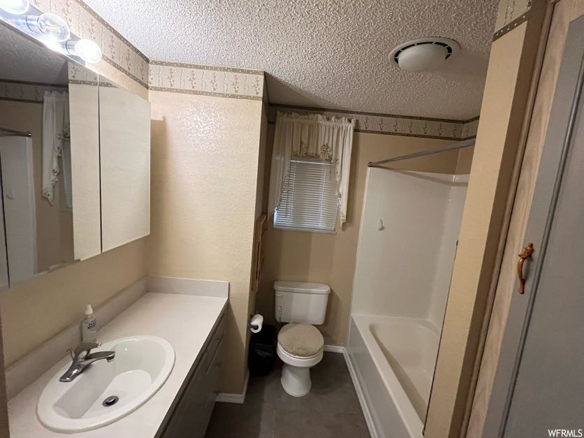 Full bathroom with shower / bath combination, a textured ceiling, large vanity, and toilet
