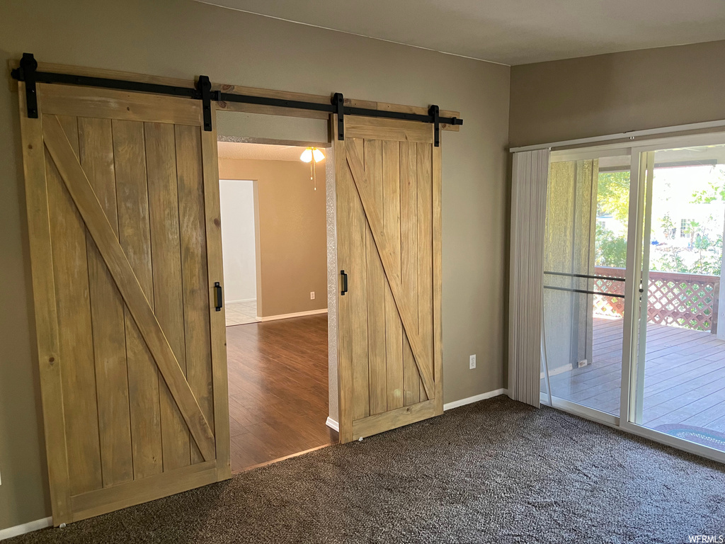Spare room featuring a barn door and dark carpet