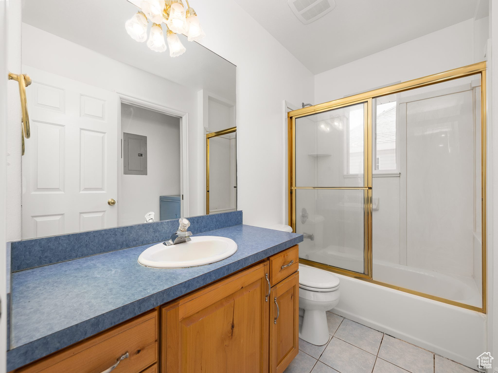 Full bathroom with tile flooring, toilet, bath / shower combo with glass door, and vanity