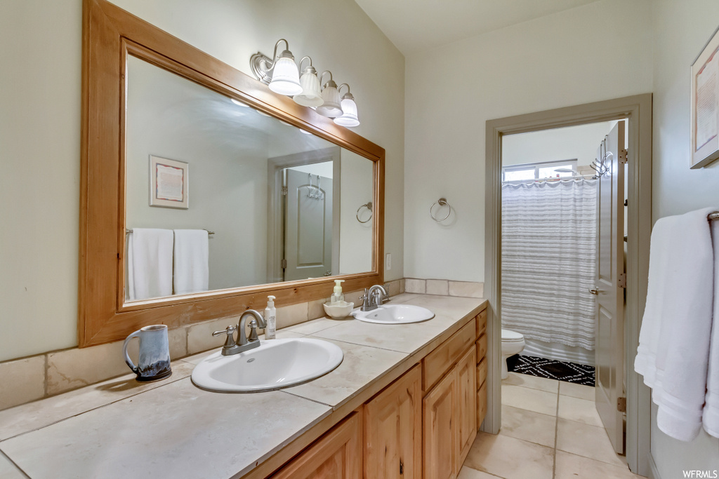 Bathroom featuring tile flooring, toilet, and double sink vanity