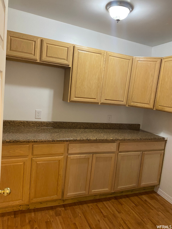 Kitchen featuring dark stone countertops and hardwood / wood-style flooring