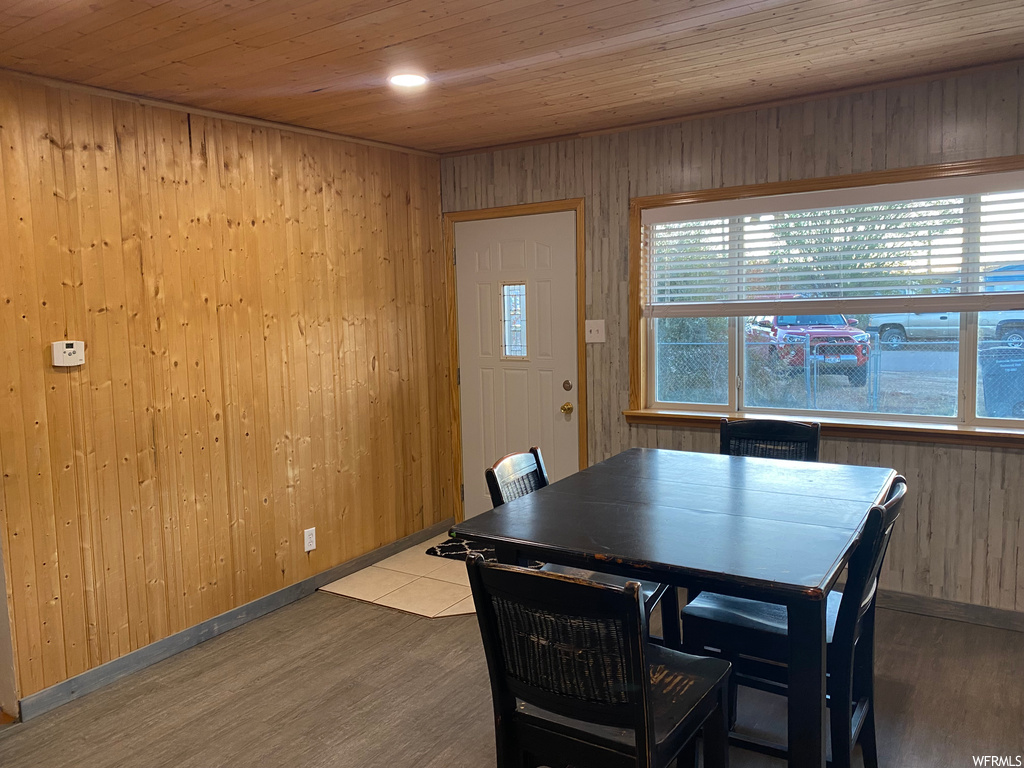 Dining space with light hardwood / wood-style floors, wooden walls, and wooden ceiling