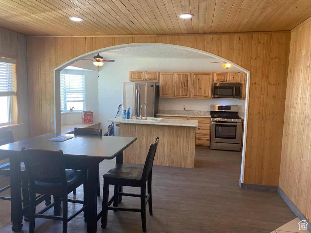 Kitchen featuring stainless steel appliances, hardwood / wood-style floors, wooden walls, and wood ceiling