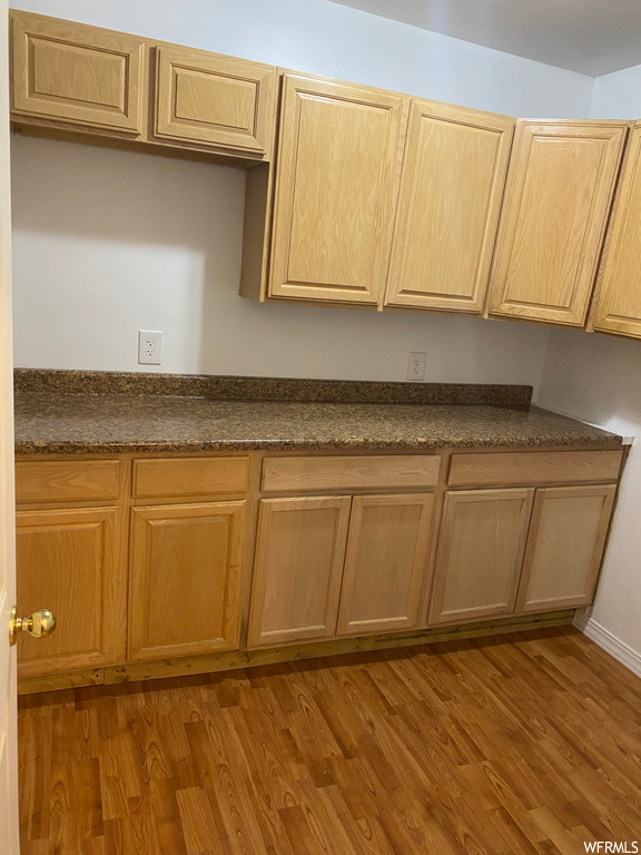 Kitchen featuring light hardwood / wood-style floors, dark stone countertops, and light brown cabinetry