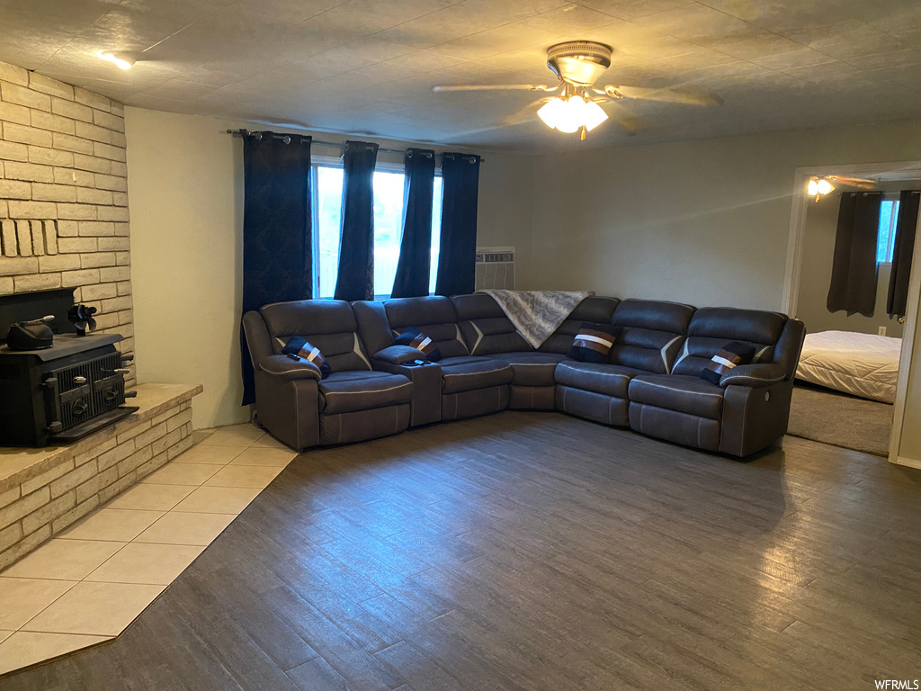 Living room featuring a brick fireplace, ceiling fan, brick wall, and light hardwood / wood-style flooring