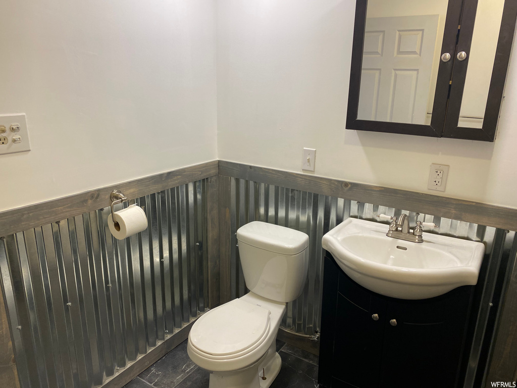 Bathroom with tile flooring, vanity with extensive cabinet space, and toilet