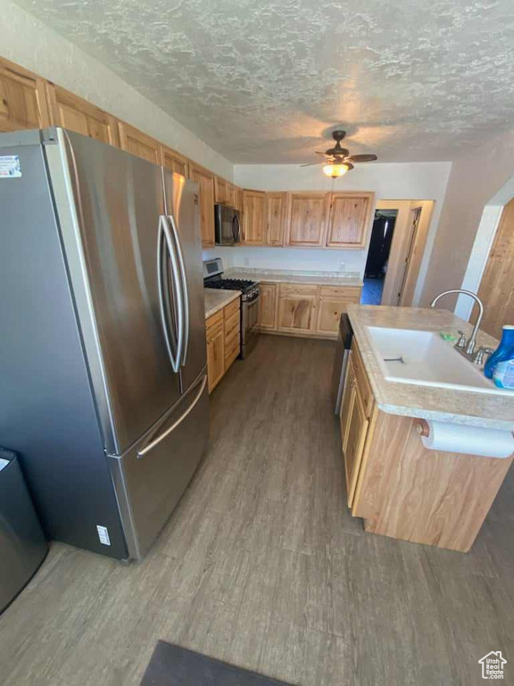 Kitchen featuring ceiling fan, hardwood / wood-style floors, and appliances with stainless steel finishes