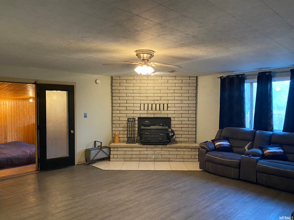 Living room featuring ceiling fan, light hardwood / wood-style flooring, a brick fireplace, and brick wall