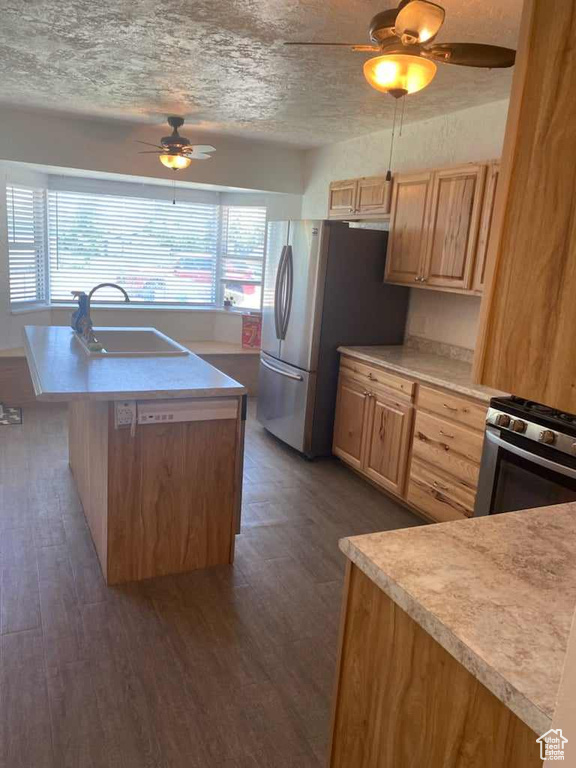 Kitchen featuring ceiling fan, stainless steel appliances, a center island with sink, dark wood-type flooring, and sink