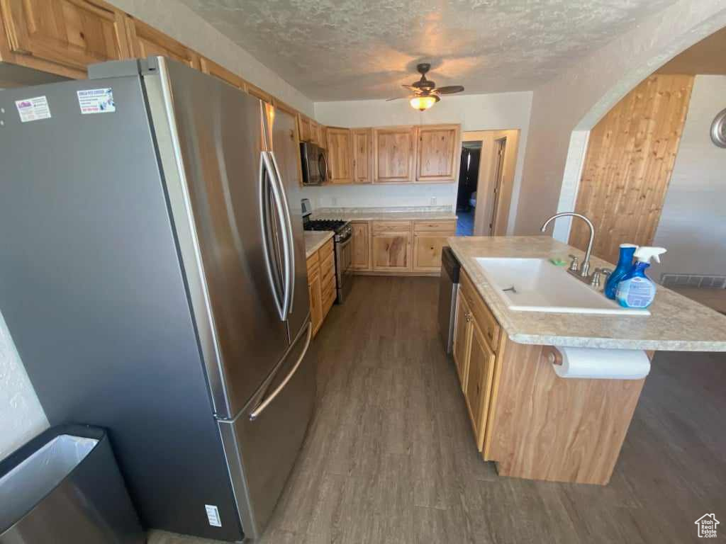 Kitchen with a center island with sink, ceiling fan, hardwood / wood-style flooring, appliances with stainless steel finishes, and sink