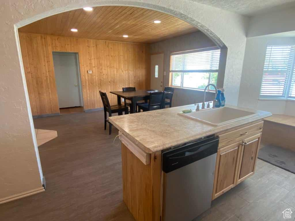 Kitchen featuring wooden walls, sink, stainless steel dishwasher, and wood-type flooring