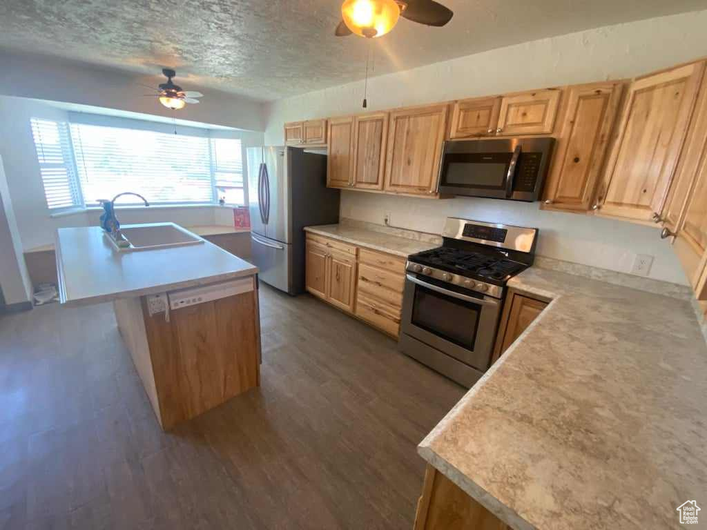 Kitchen with stainless steel appliances, ceiling fan, dark wood-type flooring, sink, and a textured ceiling