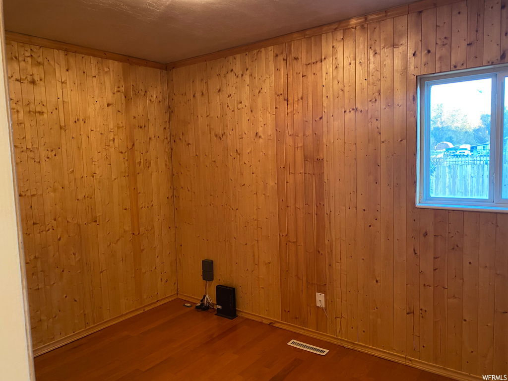 Unfurnished room with wood-type flooring and wooden walls