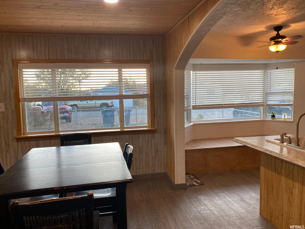 Dining area with ceiling fan, wooden walls, and dark hardwood / wood-style floors