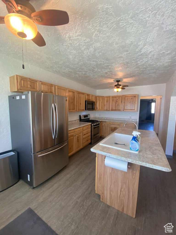 Kitchen with a textured ceiling, ceiling fan, stainless steel appliances, and hardwood / wood-style floors