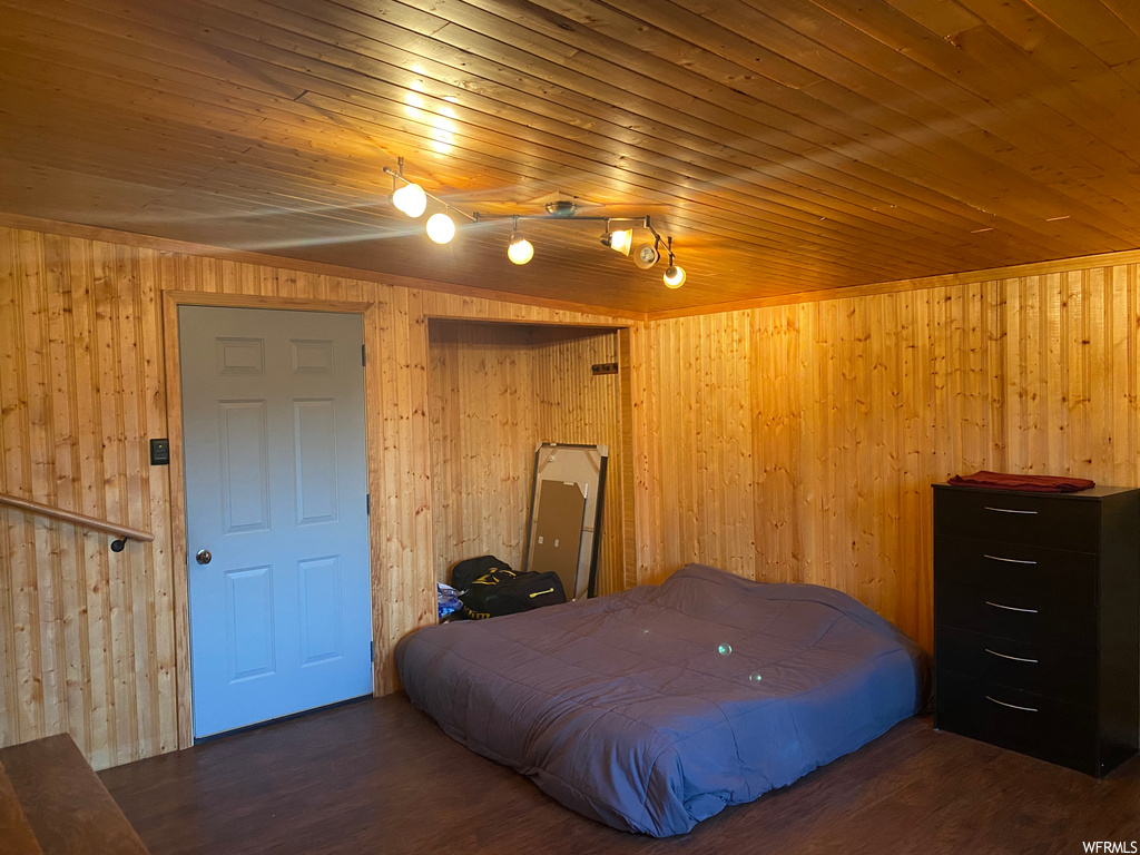 Bedroom with dark hardwood / wood-style flooring, rail lighting, wood walls, and wooden ceiling