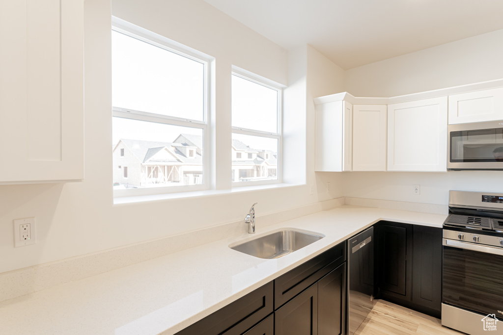 Kitchen featuring appliances with stainless steel finishes, plenty of natural light, white cabinets, and sink