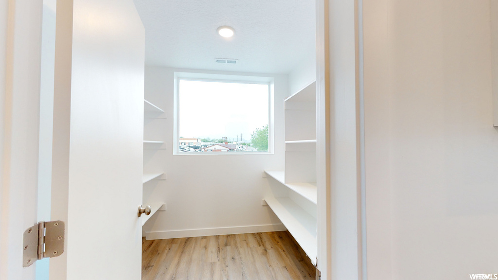 Spacious closet with light hardwood / wood-style floors