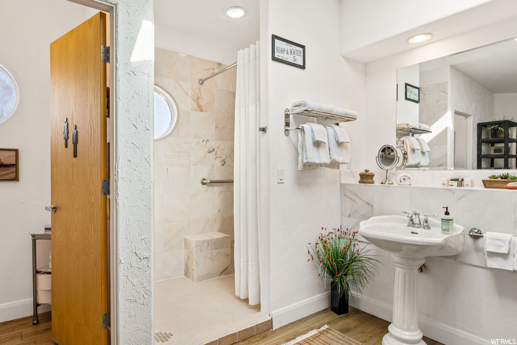 Bathroom featuring hardwood / wood-style floors, sink, and a tile shower