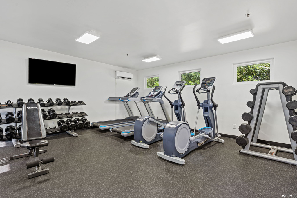 Workout area featuring plenty of natural light and a wall mounted AC
