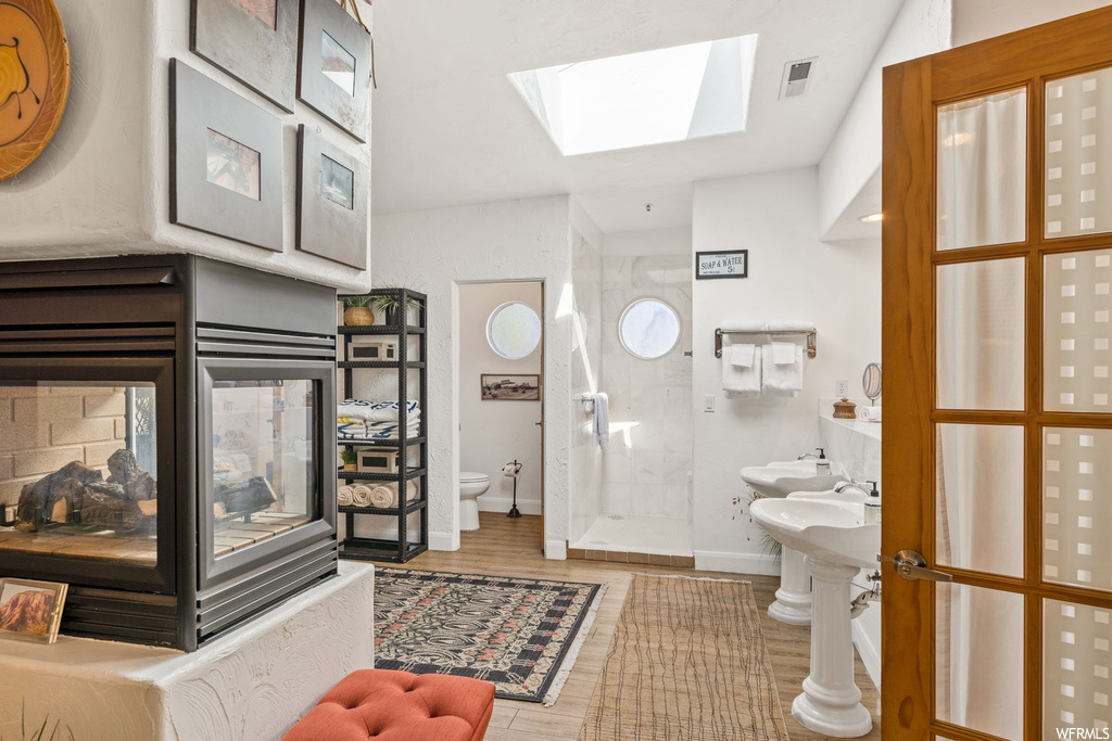 Bathroom featuring a skylight, hardwood / wood-style floors, toilet, and sink