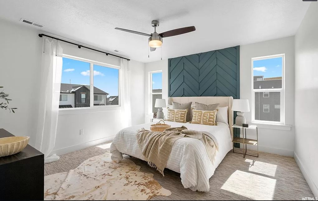 Bedroom featuring multiple windows, light carpet, and ceiling fan