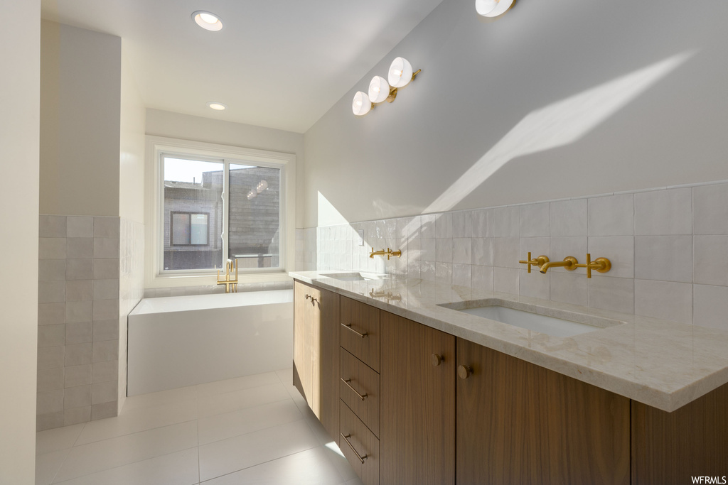 Bathroom featuring tile floors, tile walls, and dual bowl vanity
