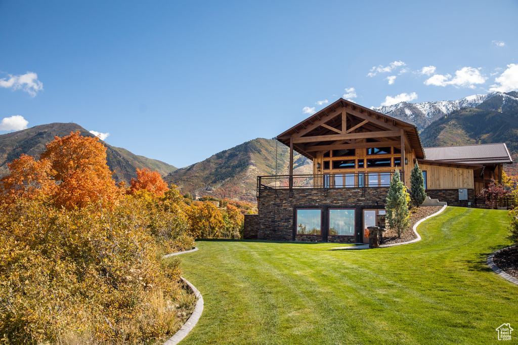 Rear view of property with a yard, a balcony, and a mountain view