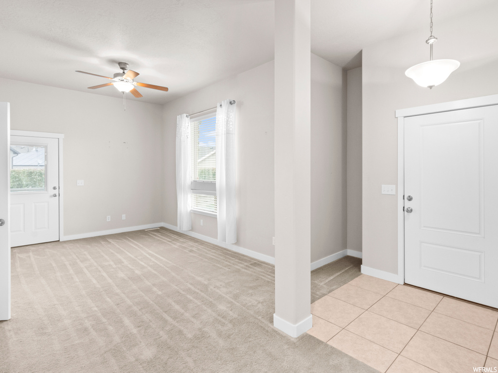 Foyer entrance with ceiling fan and light colored carpet