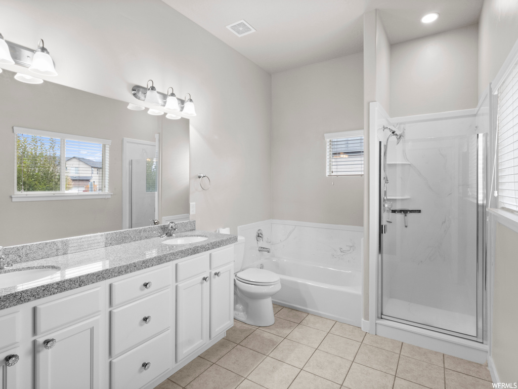 Full bathroom with double vanity, tile floors, toilet, and shower with separate bathtub