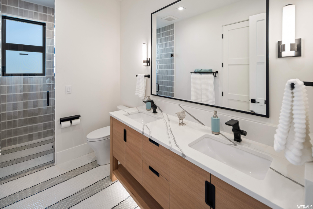 Bathroom featuring double vanity, toilet, and tile flooring