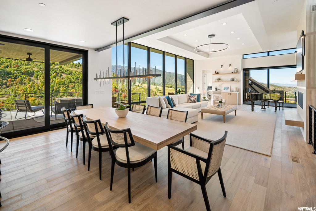 Dining space featuring light hardwood / wood-style floors, a raised ceiling, floor to ceiling windows, and ceiling fan