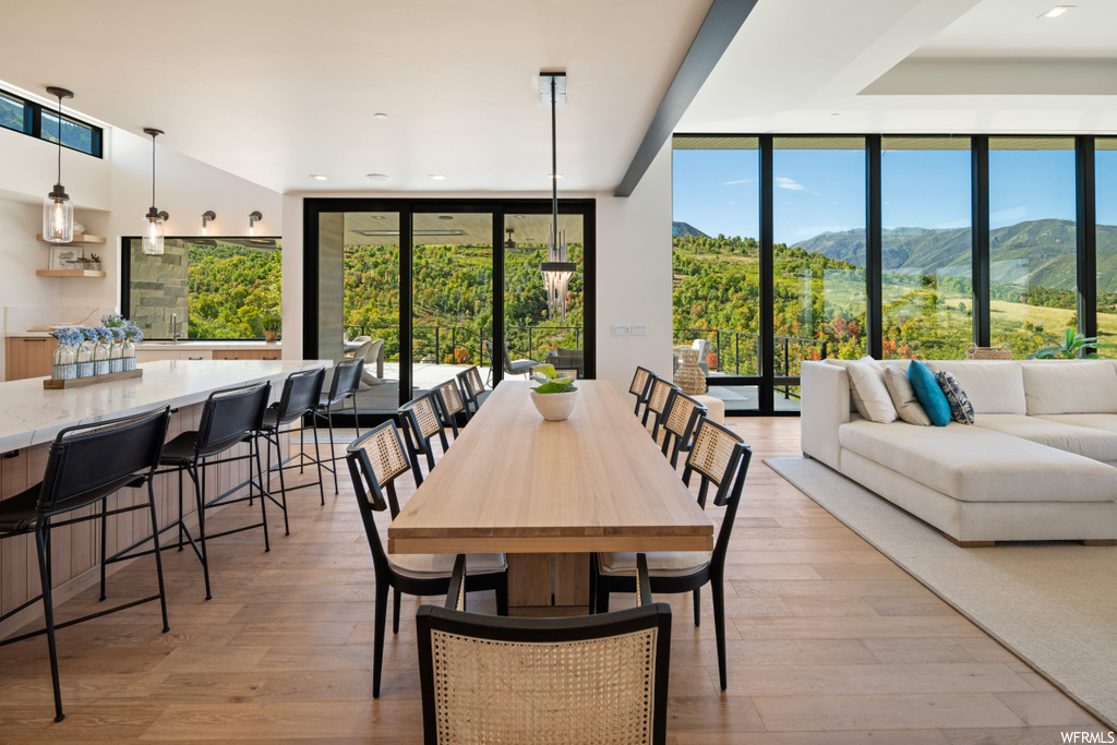 Dining space with plenty of natural light, a mountain view, light wood-type flooring, and floor to ceiling windows